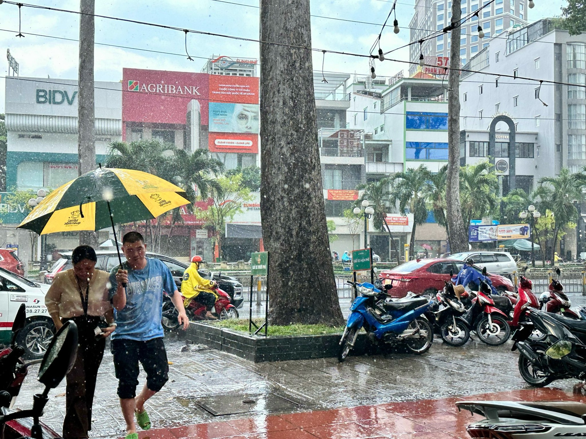 Trưa nay, TP.HCM bất chợt mưa lớn- Ảnh 1. Trên đường Nguyễn Thị Minh Khai, Q.3, mưa khá to khiến nhiều người bất ngờ. Một số người thủ sẵn áo mưa vội vã mặc tránh ướt
